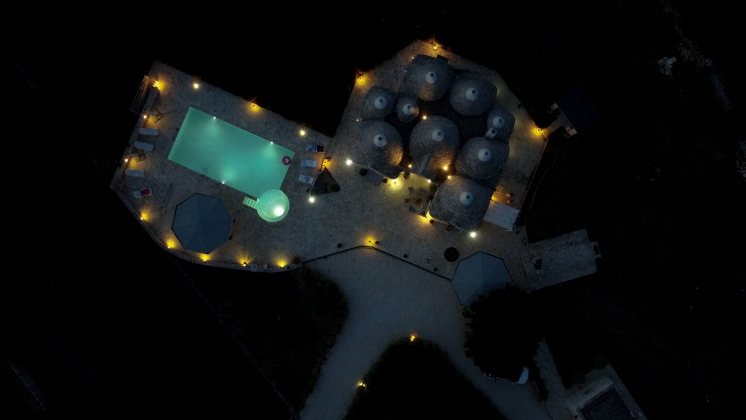 Drohnenbild Immobilie beleuchtete Villa mit Pool bei Nacht